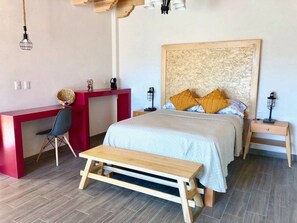 A bedroom with a bed, a desk, a chair, a bench, and two nightstands with lamps. - Oh Baja California (San Cristóbal de las Casas)