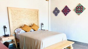A bedroom with a bed, two bedside tables, a bench, and three wall decorations. - Oh Baja California (San Cristóbal de las Casas)