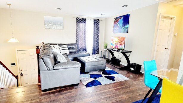Una sala de estar moderna con un sofá gris, una mesa de vidrio y un tapete azul estampado.
