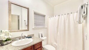 Ein Badezimmer mit Waschbecken, Spiegel, Toilette und Duschvorhang.