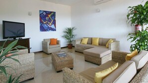 A living room with a television, a painting, and a sofa set. - Hotel Castello Budoni (Budoni)