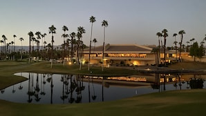 A golf course with a large building and palm trees.