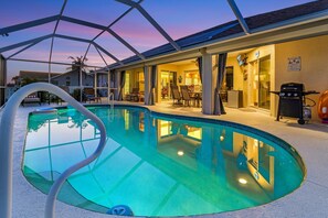 A pool area with a covered patio, a grill, and a dining area. - Southern exposure Pool, Gulf Access, - Villa Summer's Day - Roelens Vacations (Cape Coral)