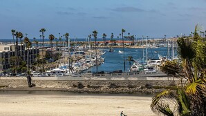Un port de plaisance avec des bateaux amarrés, des palmiers et une plage au premier plan.