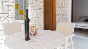 A white table with a bottle and two glasses, set against a patterned wall.
