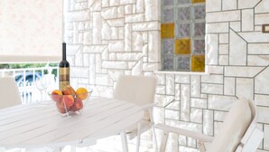 A white table with a wine bottle and a bowl of fruit.
