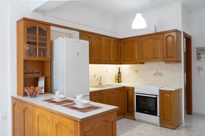 Une cuisine avec des meubles de rangement en bois, un réfrigérateur blanc, un évier et une cuisinière.