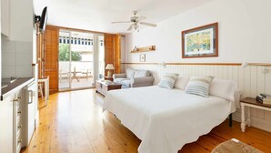 Un dormitorio con cama, escritorio, silla, ventilador de techo y ventana.