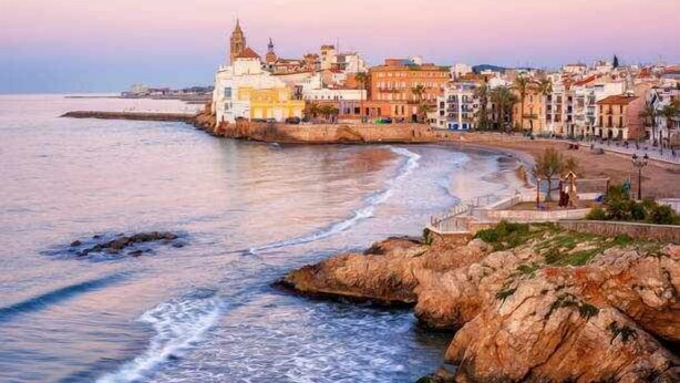 Un paisaje urbano costero con edificios a lo largo del malecón, una costa rocosa y una vista despejada del mar.