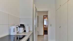 Une cuisine moderne avec un plan de travail noir, des meubles blancs et une bouilloire.