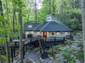 Eine Hütte mit Terrasse, Treppe und Kamin.