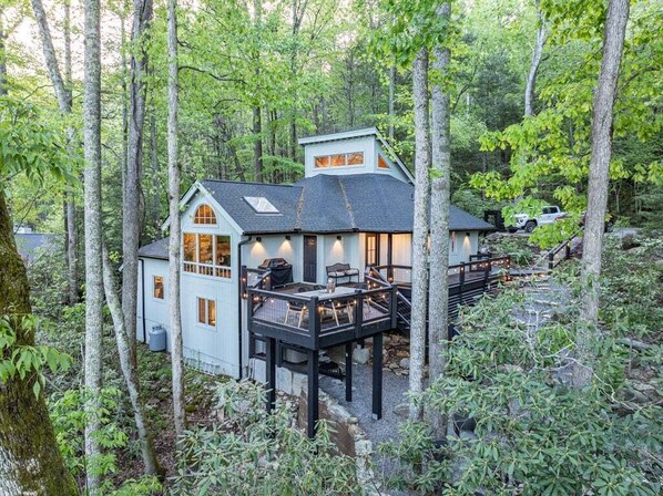Eine Hütte mit einer Terrasse, umgeben von Bäumen.