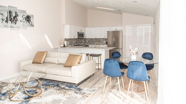 A modern living room with a white sofa, blue chairs, and a glass coffee table.