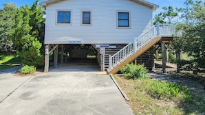 A two-story house with a covered entrance and a wooden staircase leading up to a deck. - Hameljuice - Classic 3 BR Oceanside Beach Cottage - close to beach (Southern Shores)
