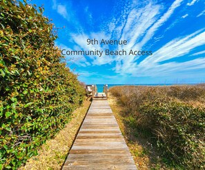 A wooden pathway leading to a beach with a clear sky.