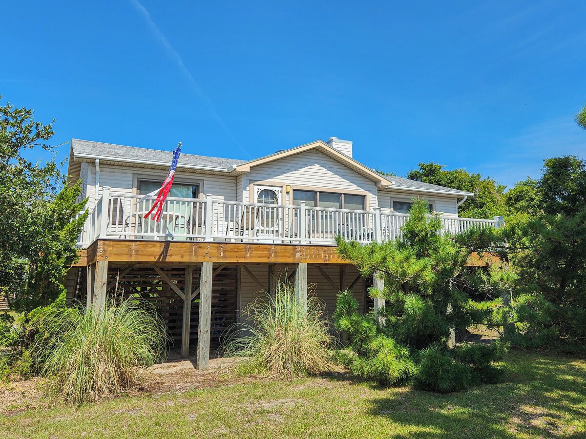 A two-story house with a wooden deck and an American flag.