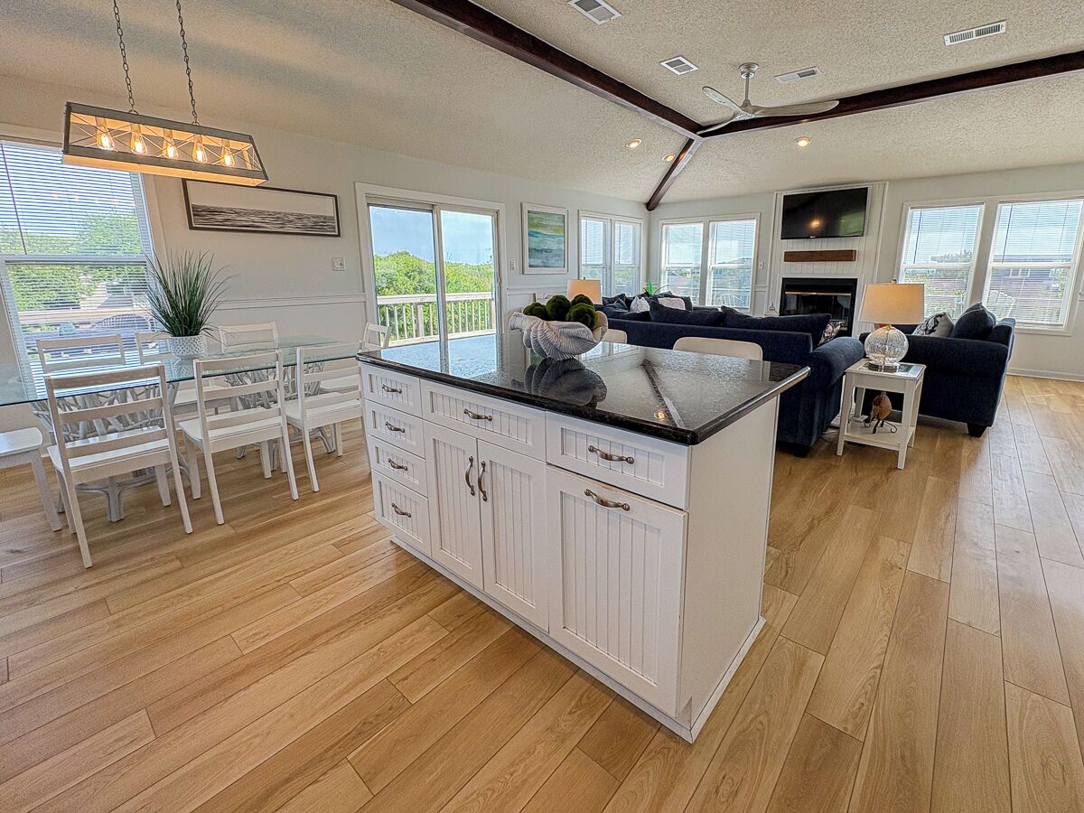 A spacious kitchen with a large island, white cabinetry, and a dining area with a glass table and chairs.