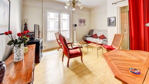 A well-lit living room with a sofa, chairs, a wooden coffee table, and a dining table.