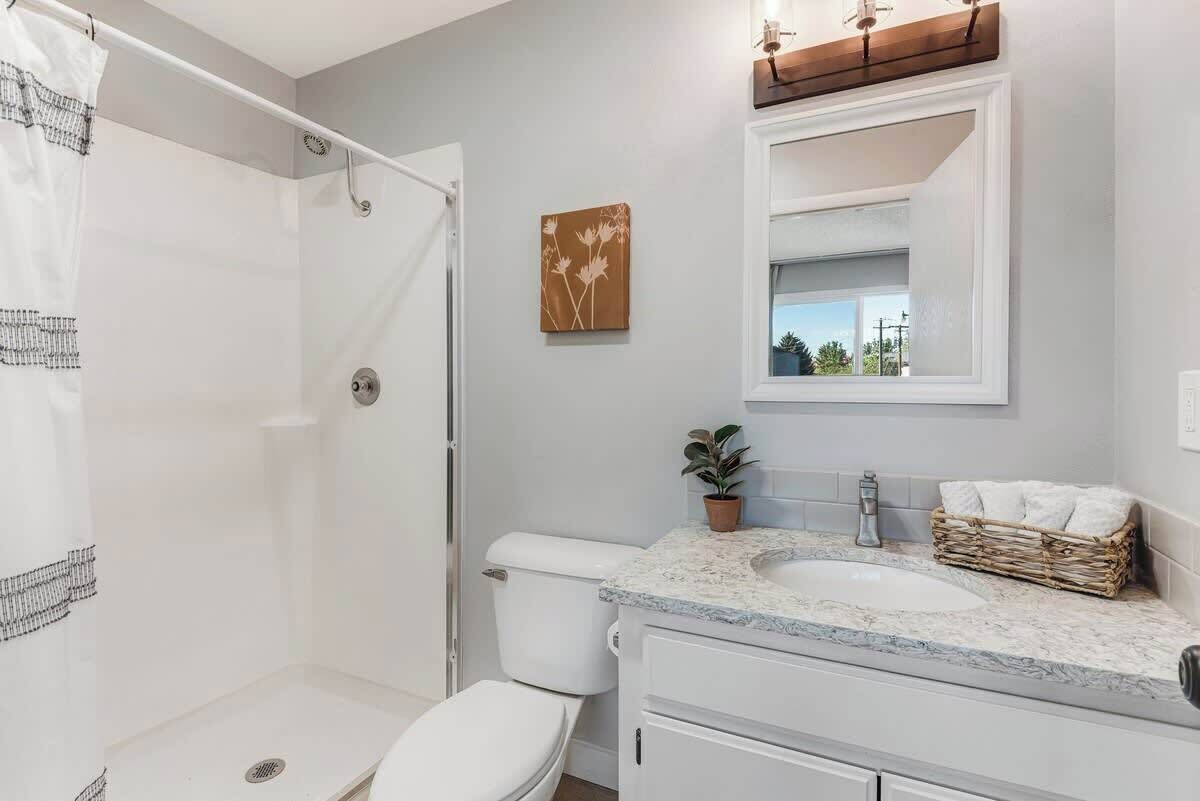 Une salle de bain équipée d’une douche, de toilettes, d’un lavabo et d’un miroir au-dessus du lavabo.