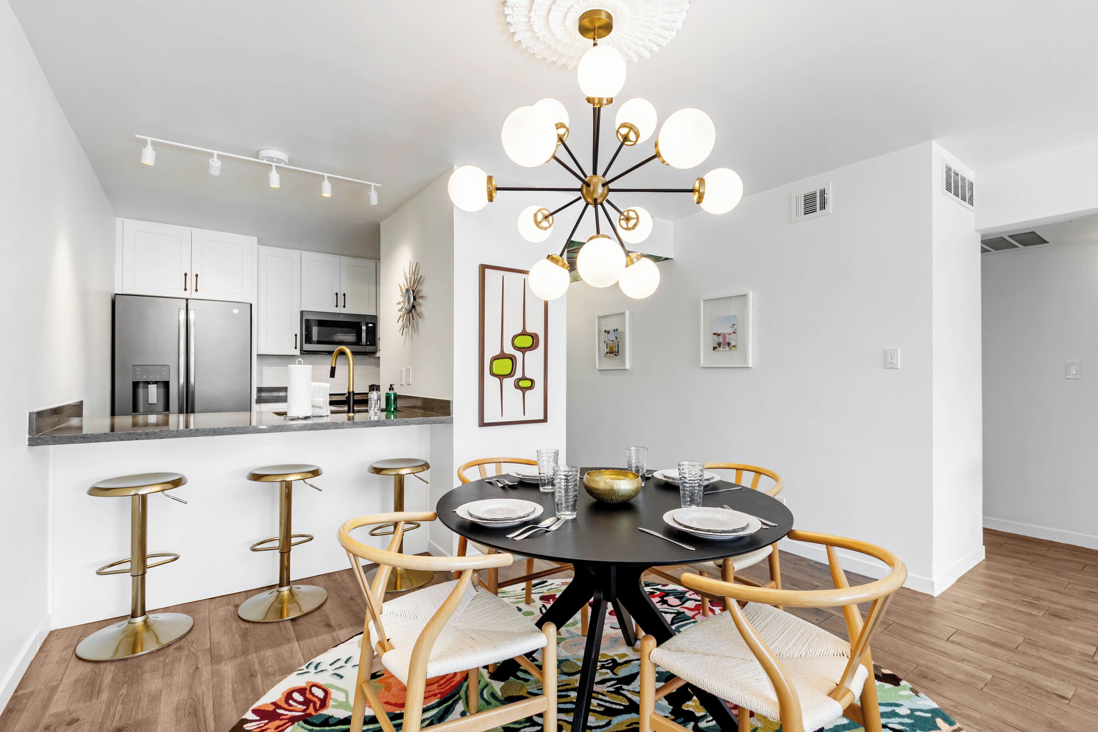 Una cocina moderna con armarios blancos, electrodomésticos de acero inoxidable y una mesa redonda con sillas.