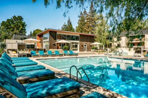 Un hotel moderno con piscina, tumbonas y vistas a árboles circundantes.
