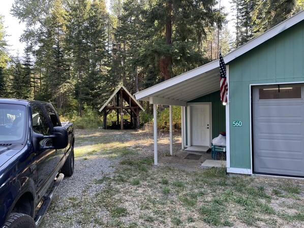 A building with a covered porch, a garage, and a small wooden structure in a forested area. - Cozy getaway in Mountains (Easton)