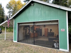 A green building with a large garage door, a private property sign, and an American flag. - Cozy getaway in Mountains (Easton)