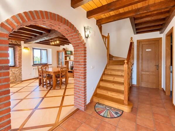 Un comedor con un arco de ladrillo, una escalera de madera y un felpudo con la inscripción 'hogar dulce hogar'.