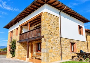 Una casa de piedra de dos pisos con balcón, vigas de madera y una pared de piedra.