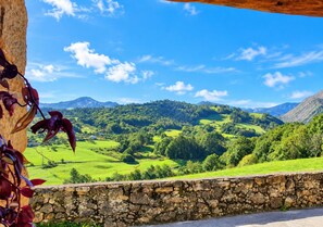 Muro de piedra con vistas a un valle verde y montañas.