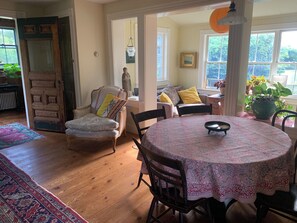 Ein gemütliches Wohnzimmer mit einem runden Tisch, einem Sessel, einer Couch und einem großen Fenster.