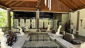 Uma área externa coberta com uma fonte de pedra, assentos e esculturas decorativas.