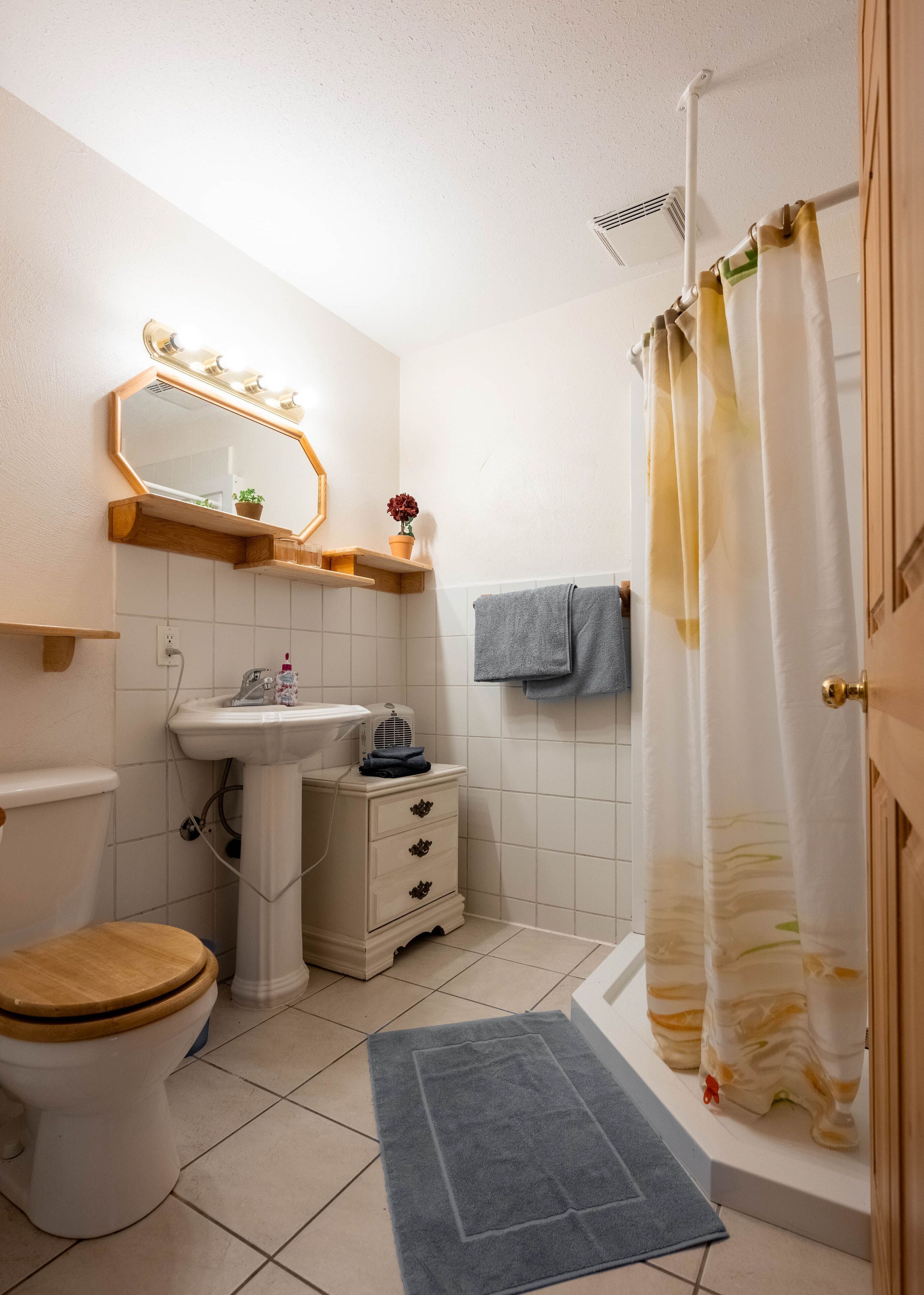 A bathroom with a toilet, sink, vanity, and shower curtain.