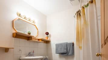 A bathroom with a toilet, sink, vanity, and shower curtain.