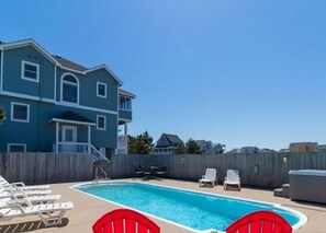 Un bâtiment à deux étages doté d’une piscine, de chaises longues et d’un jacuzzi.