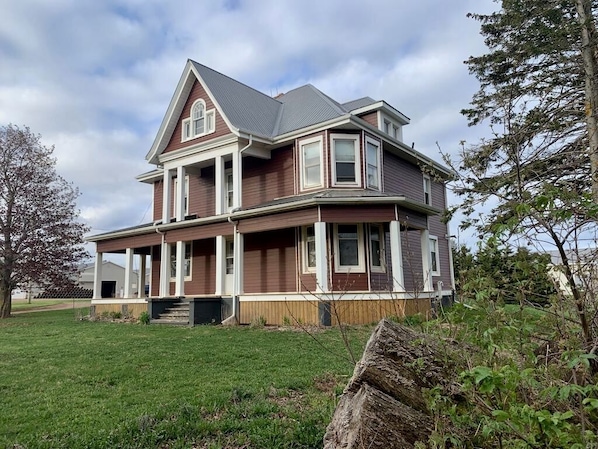 A two-story house with a gabled roof, large windows, and a covered porch.