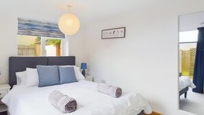 Ett sovrum med en säng, sängbord, en lampa, en spegel och ett fönster.