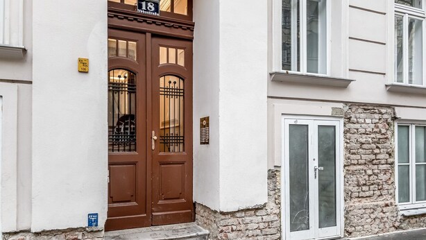 Un edificio de dos pisos con una puerta doble marrón y fachada de piedra.