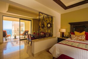 A hotel room with a bed, a desk, a chair, and a balcony with a view of the sea.