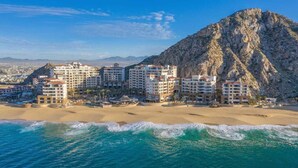Ein Küstenhotel mit mehreren Gebäuden, direkt am Strand gelegen, mit einem markanten Berg im Hintergrund.