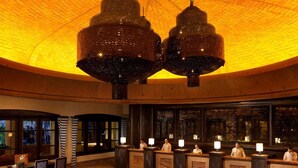 Eine Lobby mit gewölbter Decke, zwei großen Kronleuchtern, einem Empfangsbereich mit Personal und einer Sitzecke mit Stühlen.