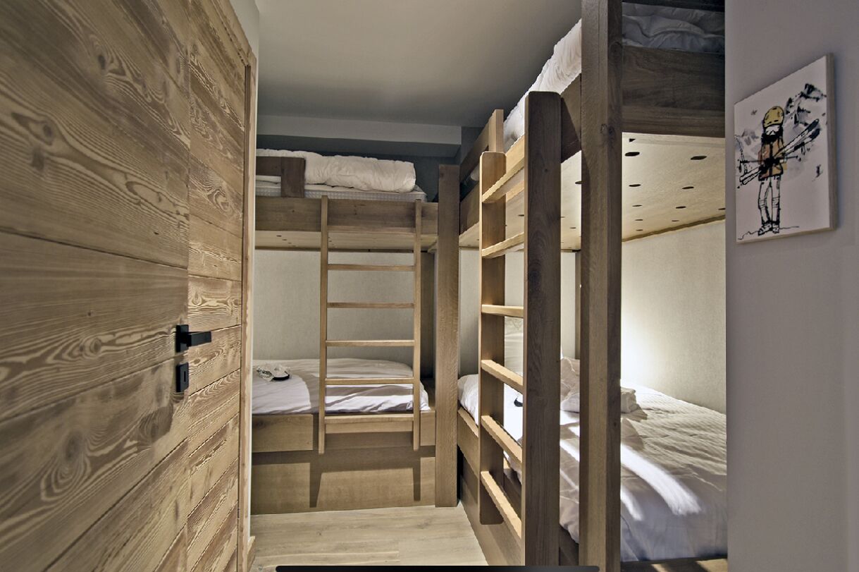 A room with bunk beds, wooden walls, and a painting on the wall.
