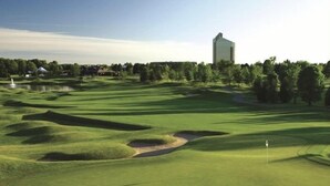 A golf course with bunkers, a flag, and a building in the background. - 28 North Extended Stay Suites!! pickleball, hot tubs! (Traverse City)
