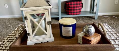 A wooden tray with a candle, a lantern, and a decorative item on a patterned carpet.