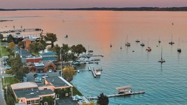 A marina with boats docked, a small building with a green roof, and a parking area with cars. - 28 North Extended Stay Suites!! pickleball, hot tubs! (Traverse City)
