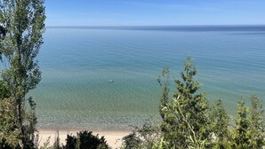 A beach with clear water and trees in the foreground. - 28 North Extended Stay Suites!! pickleball, hot tubs! (Traverse City)