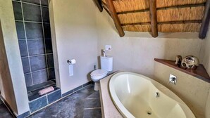 A bathroom with a bathtub, toilet, and shower area.