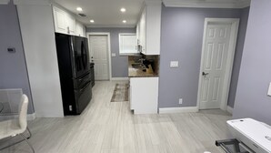 Una cocina moderna con armarios blancos, un refrigerador negro y una encimera con cafetera.