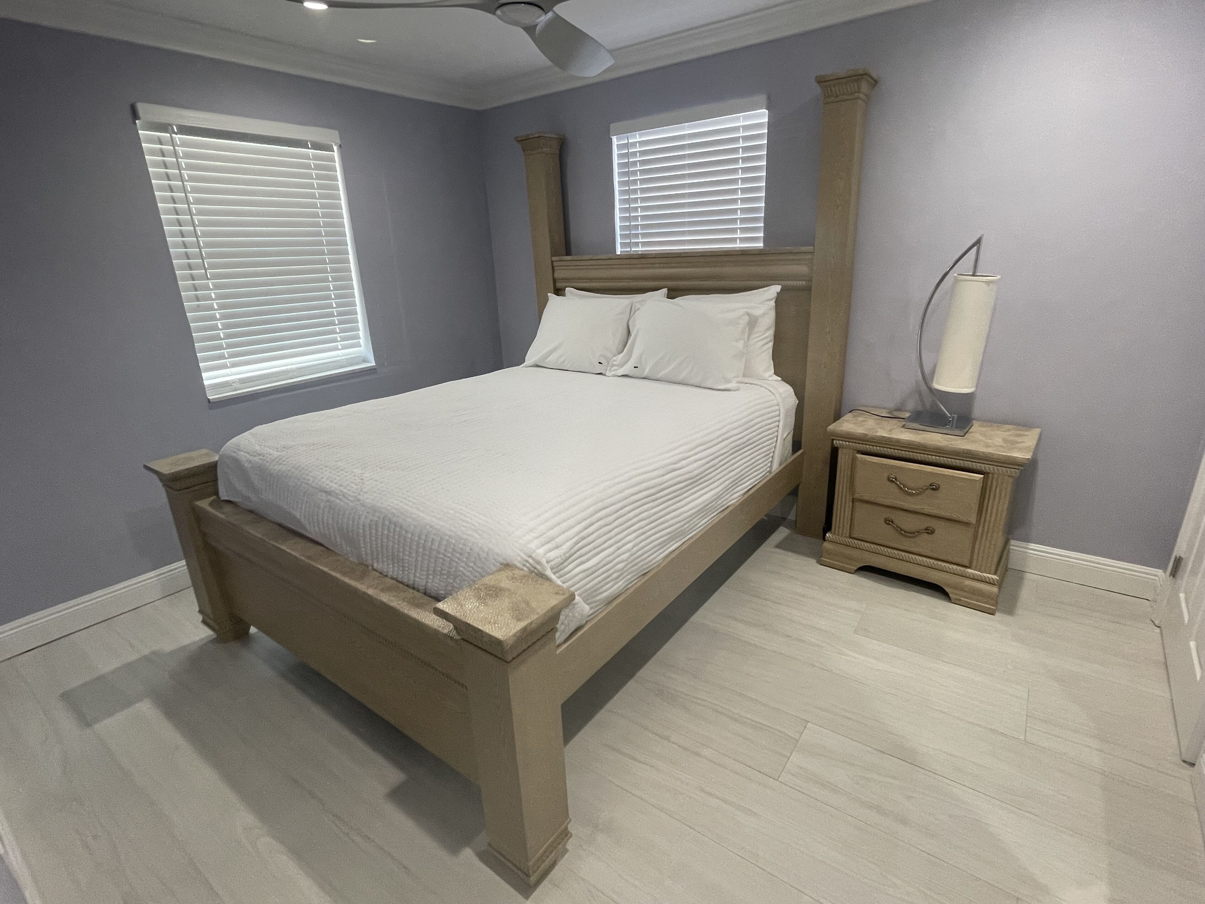 Ein Schlafzimmer mit einem hölzernen Bett, zwei Nachttischen mit Lampen und einem Deckenventilator.