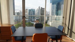 Un salón de conferencias con una gran mesa y cuatro sillas, amplias ventanas que ofrecen vistas panorámicas de la ciudad.